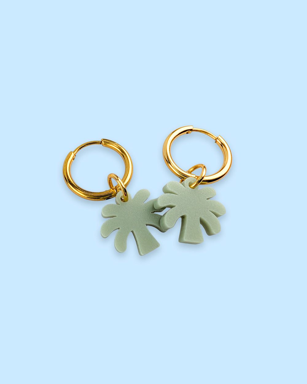 Ein Paar Creolen Ohrringe aus Edelstahl in gold mit olive-grünem Mini Palmen Anhänger aus Acrylglas. Handgemachte Design ohrringe aus Wien von sweeps.