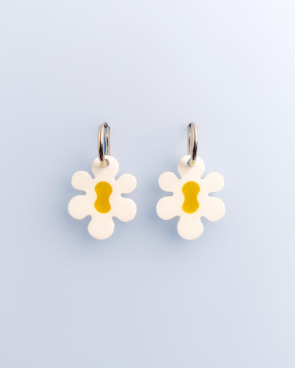 Große Retro Blumen-Ohrringe mit gelber Mitte aus Acrylglas, an silberfarbenen Edelstahl-Creolen – verspielter Modeschmuck von sweeps auf hellem Hintergrund.