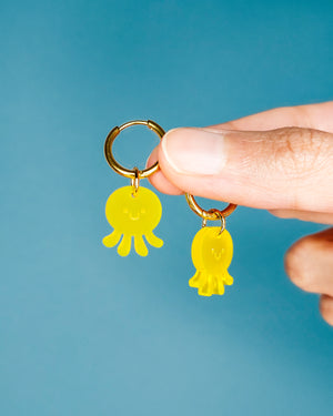 Hand hält Octopuss-Ohrringe aus gelben Acrylglas mit goldenen Edelstah Creolen von sweeps.