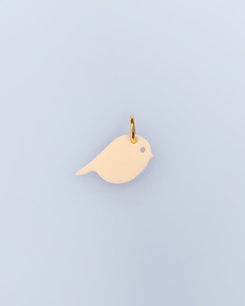 Ein elfenbeinfarbene Vogel-Schmuck-Anhänger aus Acrylglas mit Edelstahlring – sweeps mix and match 