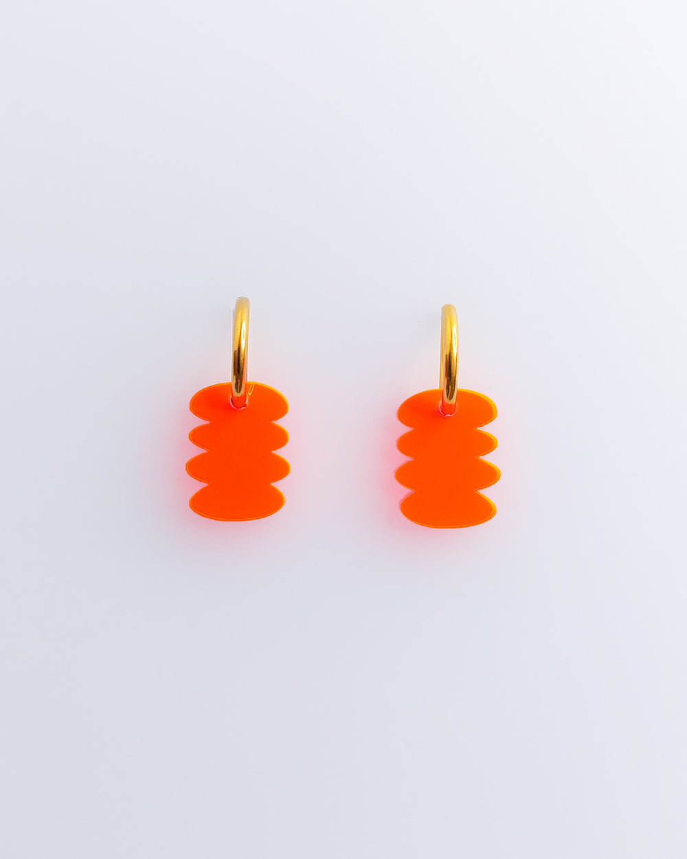 Zwei Ohrringe mit Neon orangen grafischen Anhängern aus Edelstahl und Acrylglas.