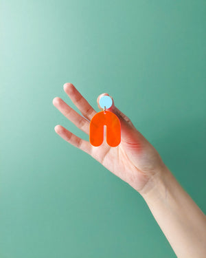 Hand hält einen großen colorblock  Ohrstecker Ohrring aus Acrylglas in Bogenform von sweeps 