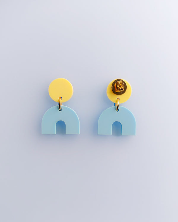 Zwei Duotone Ohrstecker mit gelbem Kreis und hellblauem Bogen aus Acrylglas, mit Edelstahlstecker von sweeps.