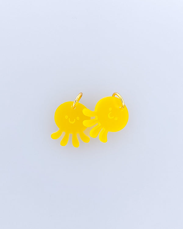 Zwei gelbe Quallen Ohrring oder Schmuckanhänger mit graviertem Gesicht aus satiniertem Acrylglas und vergoldeten Edelstahl-Ringen.