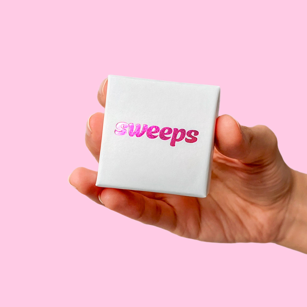 Frau hält weisse Schmuckschachtel von sweeps Acrylschmuck mit pinkem Logo 